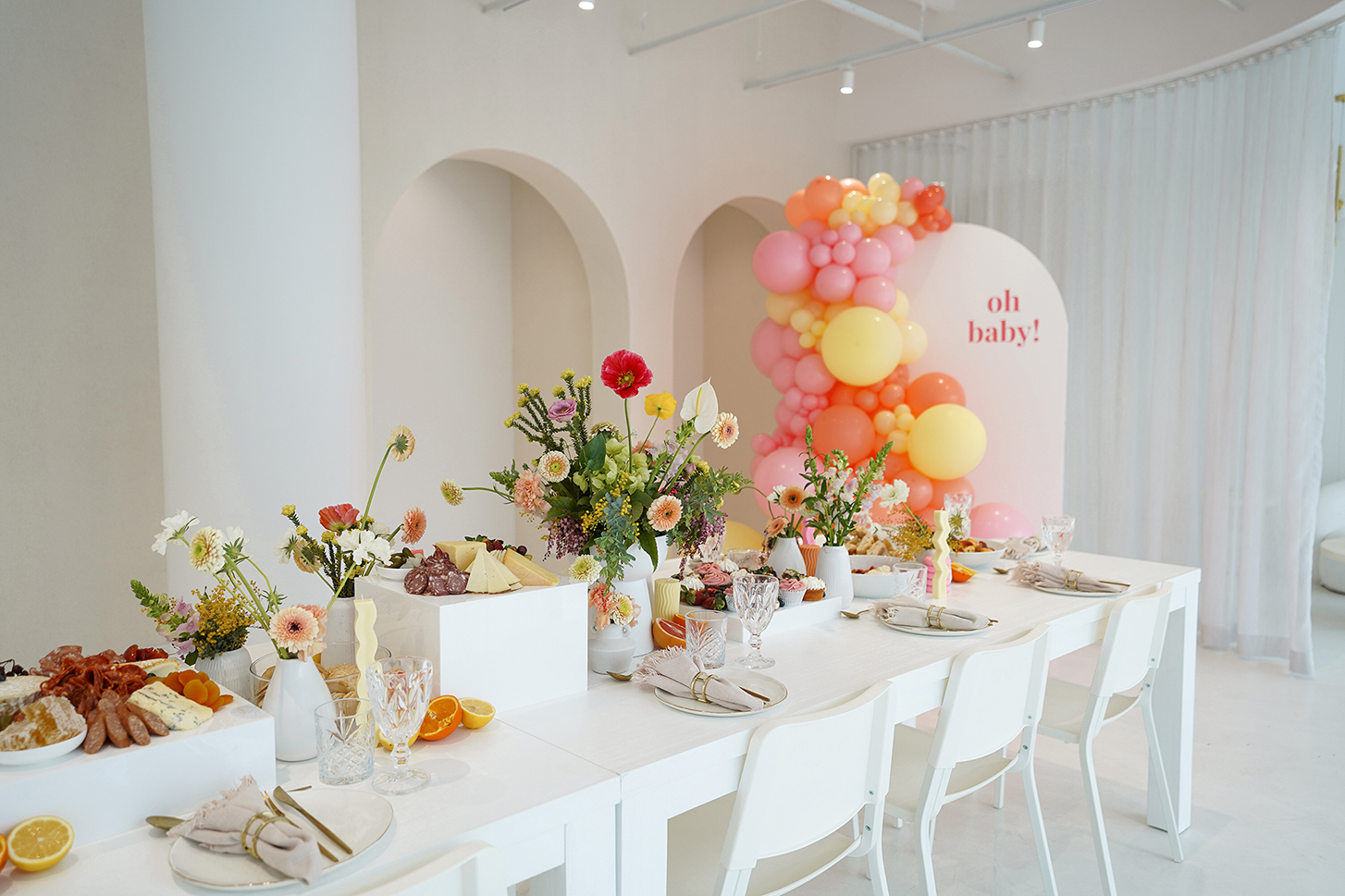 white table with floral arrangements atop and a pink sign with oh baby on it in a darker pink
